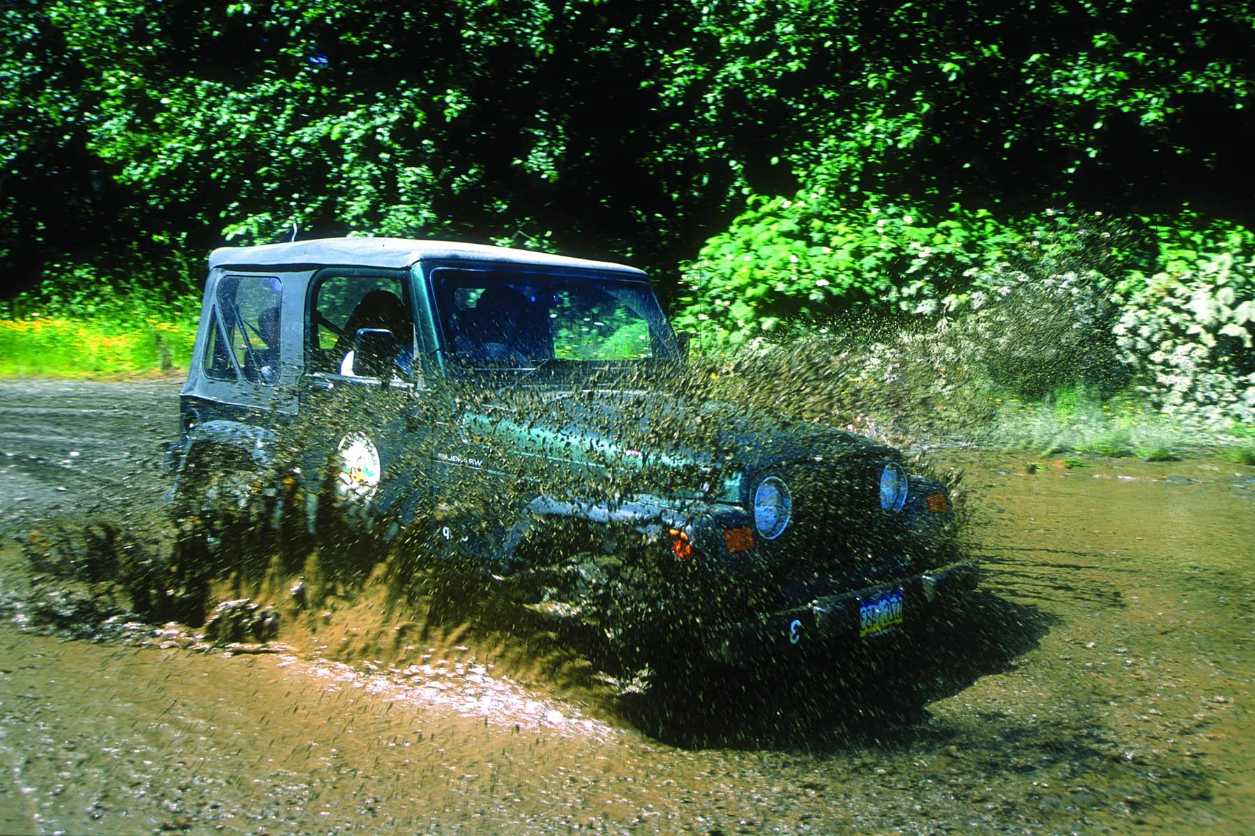 A Jeep Wrangler crossing a shallow stream on a Ketchikan logging road